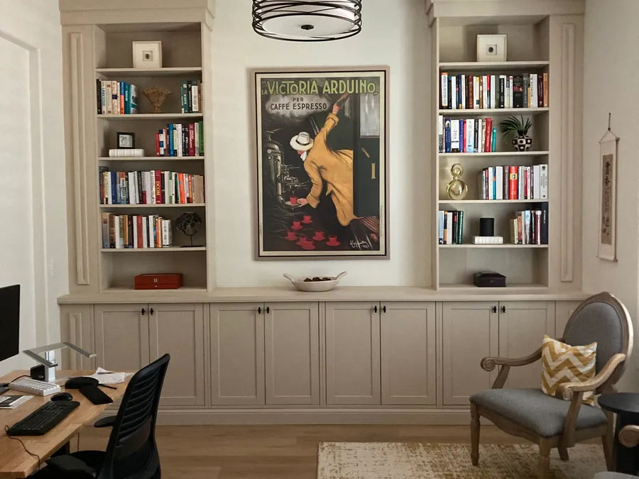 Home office built-in cabinets and bookshelves flanking a framed poster, by Desert Forge Cabinets