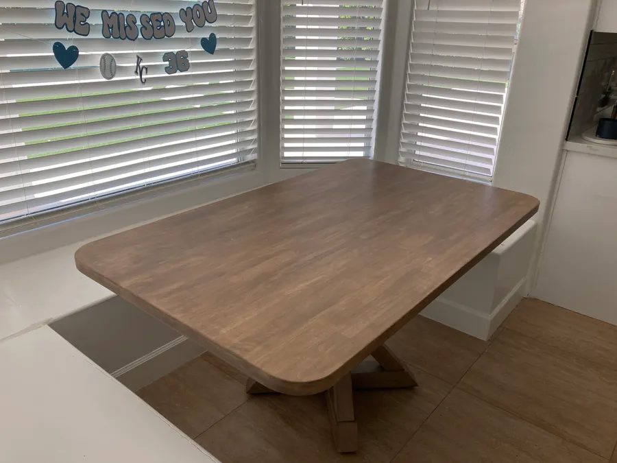 Solid wood dining table in a breakfast nook with plantation shutters, by Desert Forge Cabinets