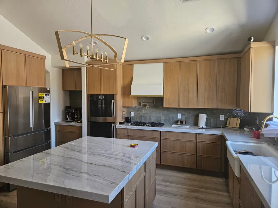 White oak custom kitchen cabinets with a marble-top island and brass light fixture, by Desert Forge Cabinets